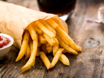 Frisch frittierte Pommes mit Ketchup auf Holzuntergrund
