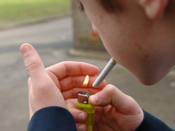 Jugendlicher zündet sich mit Feuerzeug eine Zigarette an