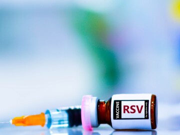 Liegendes Vial mit Aufschrift „Vaccine RSV“ und im Hintergrund eine Spritze
