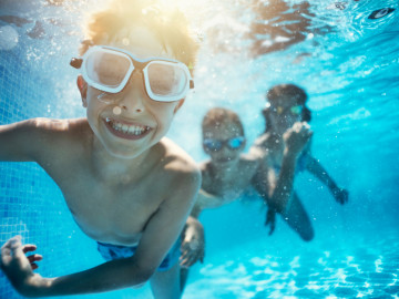 Kinder mit Taucherbrille unter Wasser im Schwimmbad