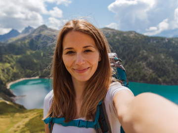 Frau macht Selfie vor Bergpanorama