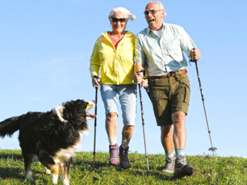 Seniorenpaar mit Hund beim Nordic Walking