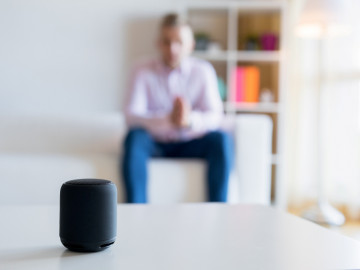 Mann unscharf im Hintergrund spricht mit smart speaker