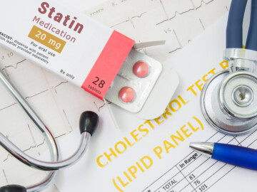 Medikamentenpackung mit Aufschrift Statin, Stethoskop und Kugelschreiber liegen auf auf EKG-Ausdruck