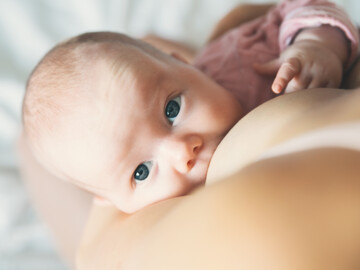 Baby wird getillt und blickt in die Kamera