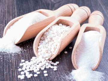 Holzschaufeln mit Zucker, Süßstoff und weißen Tabletten