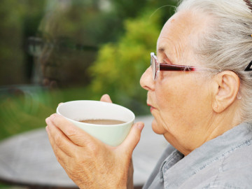 ältere Frau mit Teetasse in der Hand