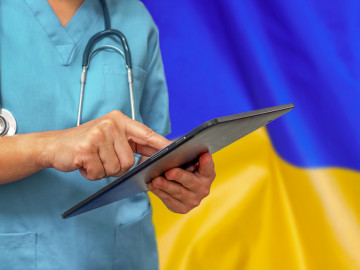 Arzt mit Tablet vor der ukrainischen Flagge