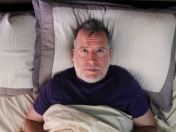 Mann liegt wach im Bett