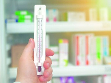 Thermometer vor Apothekenregal im Hintergrund