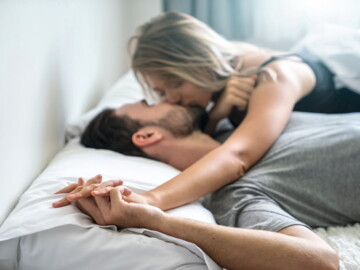 Mann und Frau küssen sich im Bett.