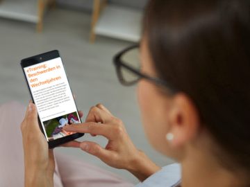 Frau schaut sich eTraining Wechseljahresbeschwerden auf dem Handy an.