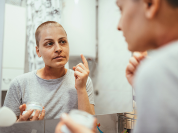 Chemopatientin mit Kosmetik vorm Spiegel