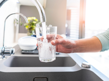 Glas unterm Wasserhahn mit Wasser befüllen