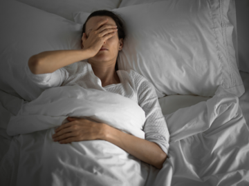 Frau mit Kopfschmerzen im Bett
