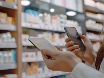 Frau mit Handy und Taschenrechner in der Apotheke